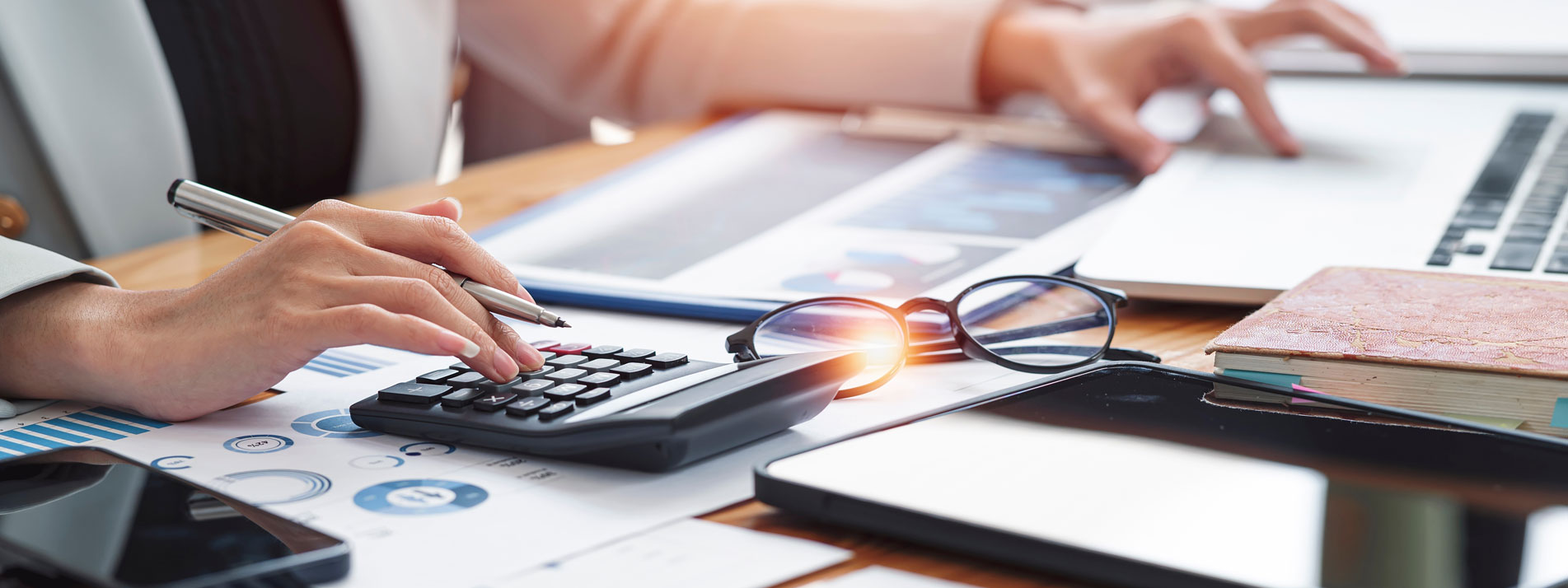 Calculating taxes with a calculator and sun reflecting off of glasses